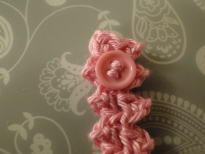 Pink button sewn onto pink bracelet Pink button sewn onto pink bracelet