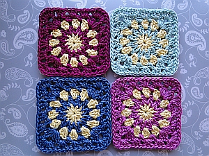 The four coasters shown in magenta, green, blue and pink, each combined with a yellow sun pattern.