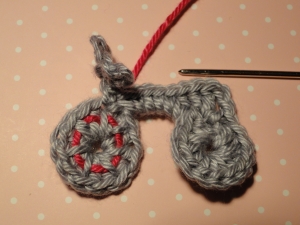 Crimson yarn woven under and over wheel stitches