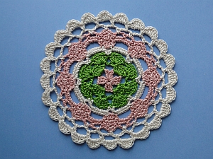 Coaster worked in pink, green, and cream