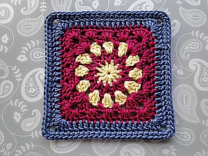 Cosmic Crochet Square with a yellow center, crimson middle, and dark blue edging.